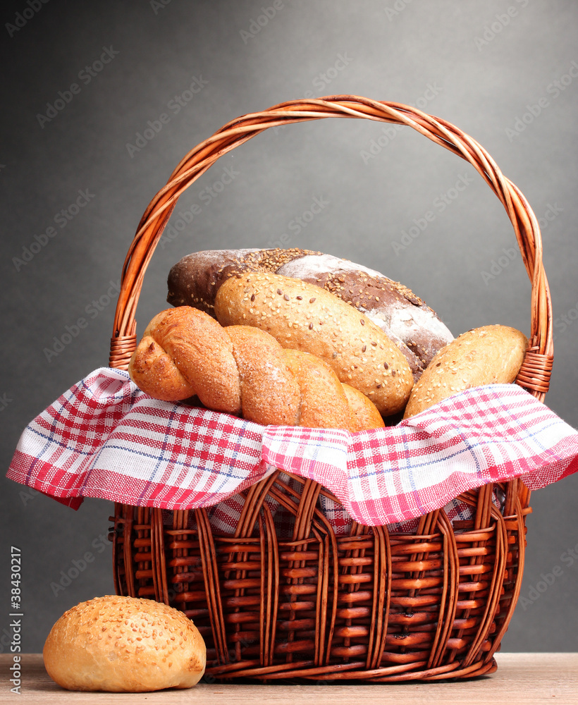 delicious bread in basket on wooden table on gray background