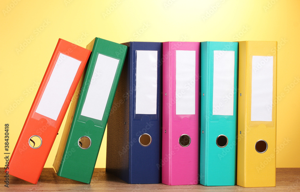 bright office folders on wooden table on yellow background bright office folders on wooden table on yellow background