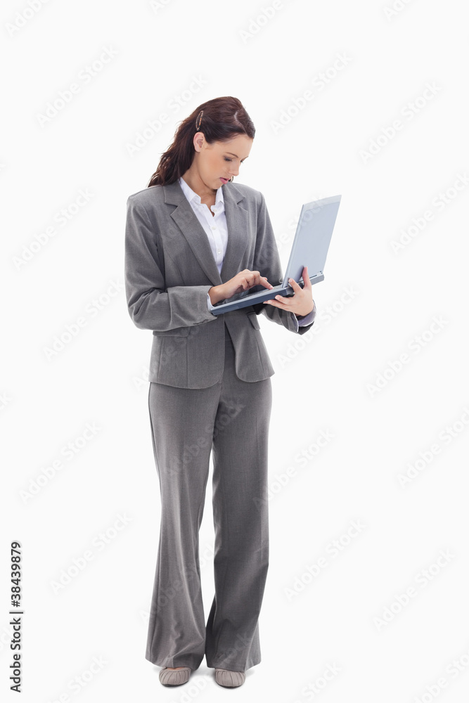 Businesswoman standing and typing on a laptop Businesswoman standing and typing on a laptop