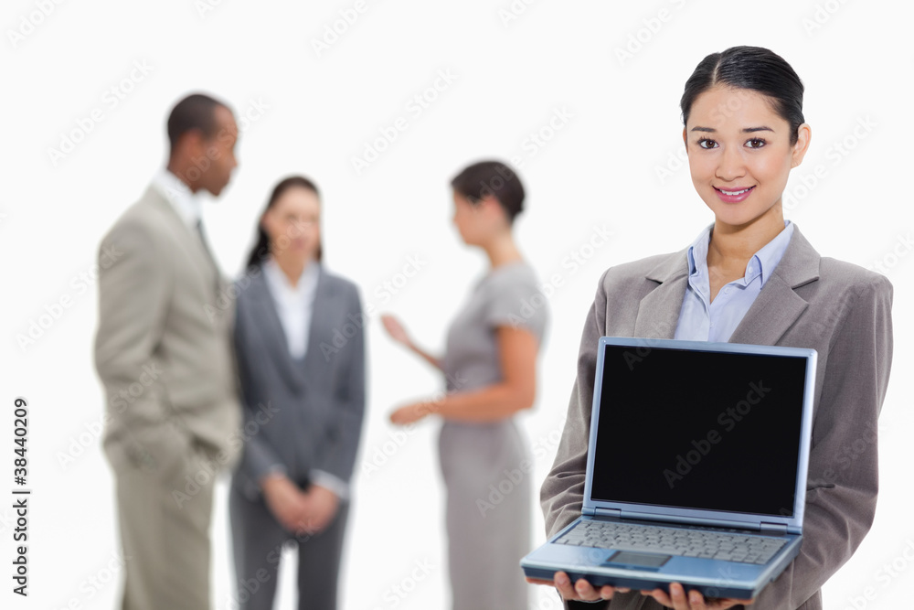 Businesswoman smiling showing a laptop screen with co-workers in Businesswoman smiling showing a laptop screen with co-workers in