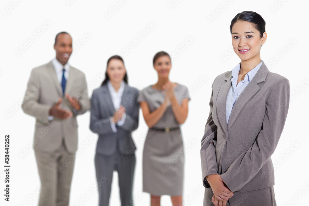 Businesswoman with co-workers applauding in the background Businesswoman with co-workers applauding in the background