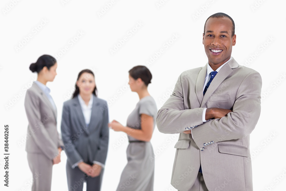 Businessman smiling with three co-workers talking in the backgro Businessman smiling with three co-workers talking in the backgro