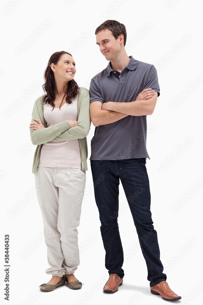 Smiling couple looking at each other and crossing their arms Smiling couple looking at each other and crossing their arms