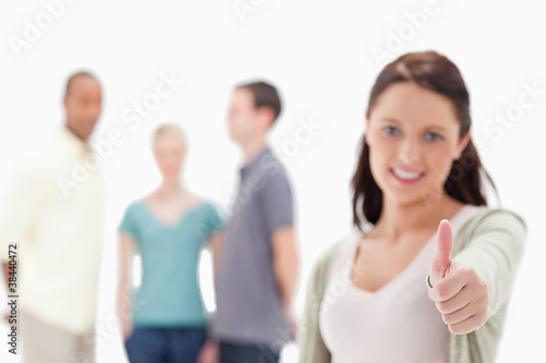 Close-up of a woman giving the thumbs-up with friends