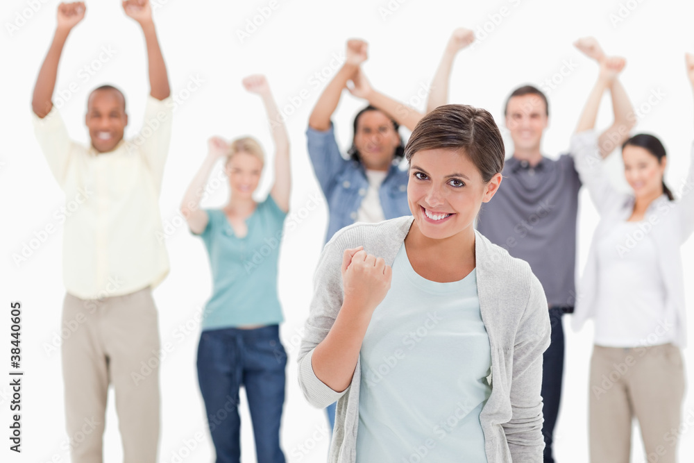 Woman clenching her fist with people behind raising their arms Woman clenching her fist with people behind raising their arms