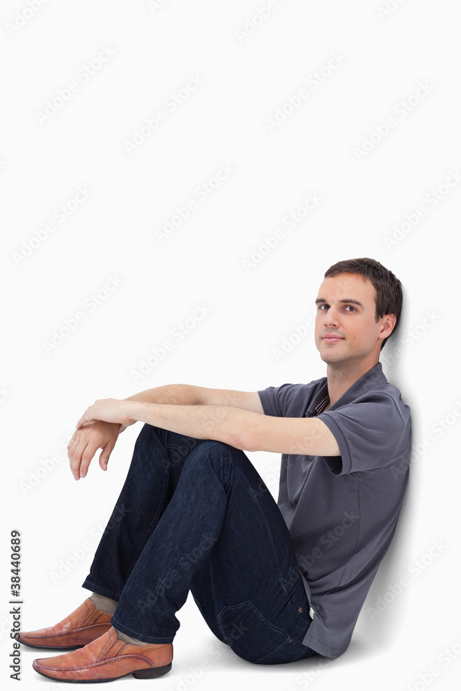 Close-up of a dark brown hair man sitting against a wall Close-up of a dark brown hair man sitting against a wall