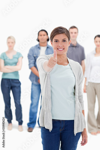 Close-up of a woman giving the thumb-up with people behind