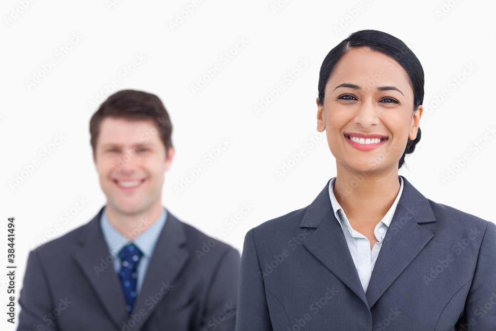 Close up of smiling saleswoman with colleague behind her Close up of smiling saleswoman with colleague behind her