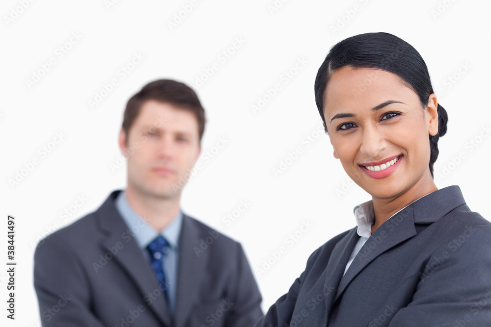 Close up of smiling saleswoman with co-worker behind her Close up of smiling saleswoman with co-worker behind her