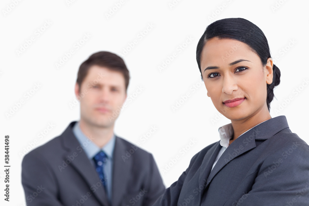 Close up of confident saleswoman with co-worker behind her Close up of confident saleswoman with co-worker behind her