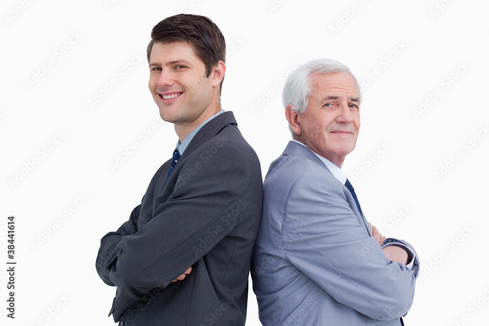 Close up of businessman and his mentor standing back to back Close up of businessman and his mentor standing back to back