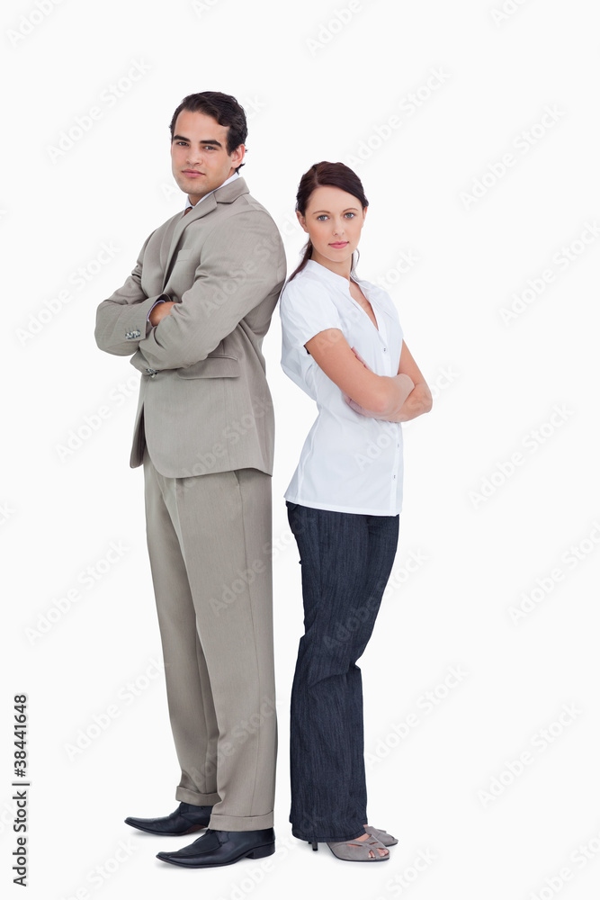 Serious salesteam with arms folded standing back to back Serious salesteam with arms folded standing back to back