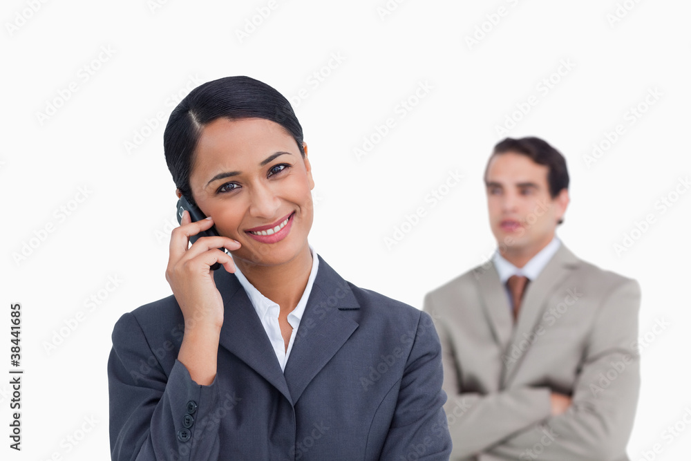 Smiling saleswoman on her mobile phone and colleague behind her Smiling saleswoman on her mobile phone and colleague behind her