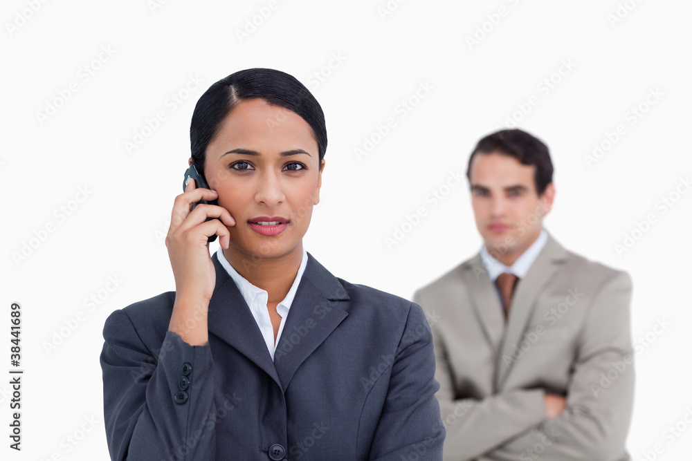 Saleswoman on her cellphone with colleague behind her Saleswoman on her cellphone with colleague behind her