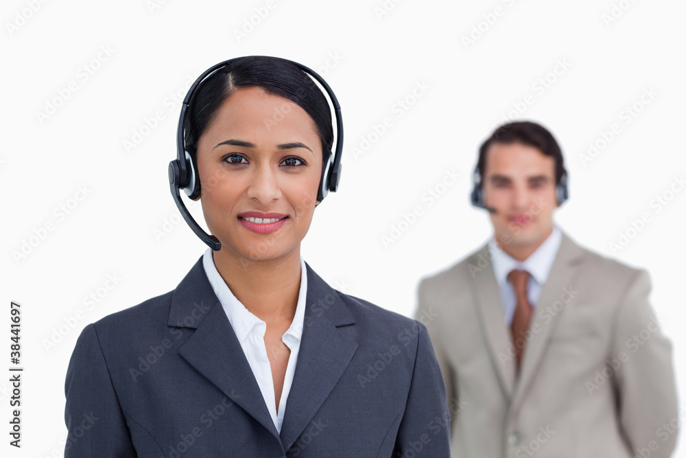 Smiling telephone support worker with colleague behind her