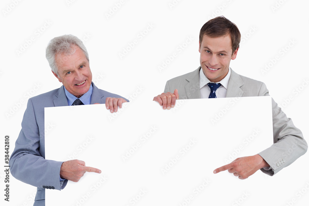 Smiling tradesmen pointing at blank sign in their hands Smiling tradesmen pointing at blank sign in their hands