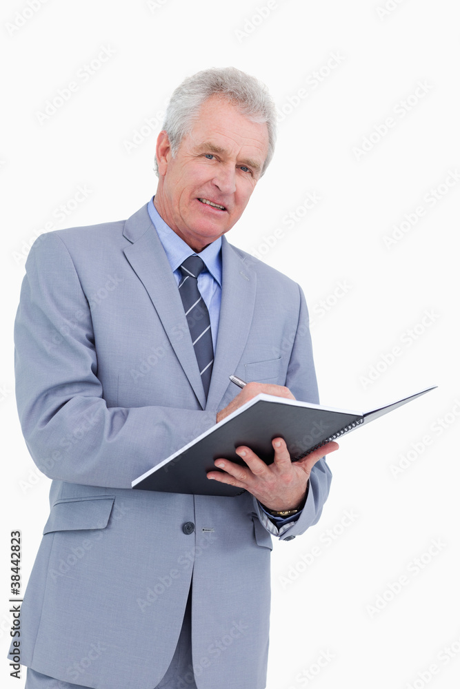Smiling mature tradesman with pen and notebook Smiling mature tradesman with pen and notebook