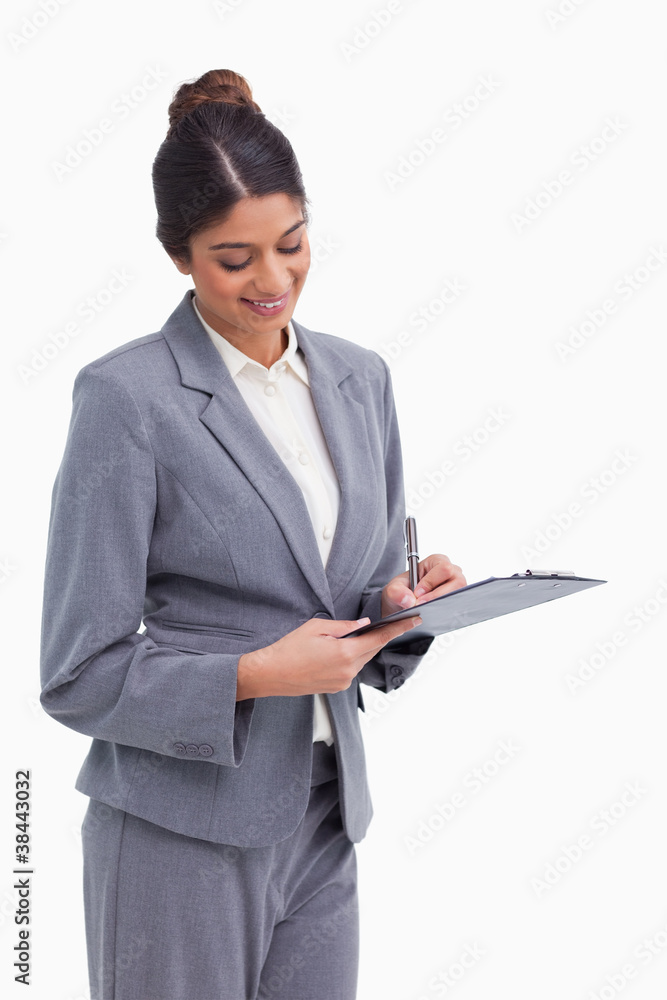 Smiling female entrepreneur taking notes on clipboard Smiling female entrepreneur taking notes on clipboard