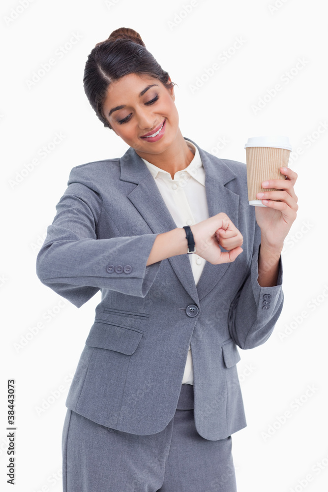 Smiling female entrepreneur with paper cup looking at her watch Smiling female entrepreneur with paper cup looking at her watch