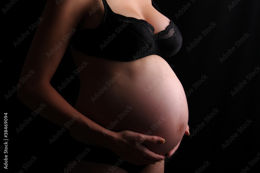 Pregnant woman touching her belly with hands, dark barkground Pregnant woman touching her belly with hands, dark barkground