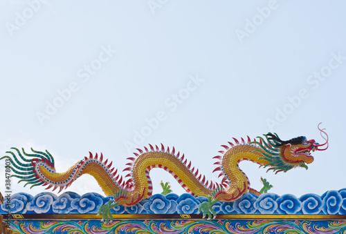 golden Chinese Dragon on roof with blue sky background.