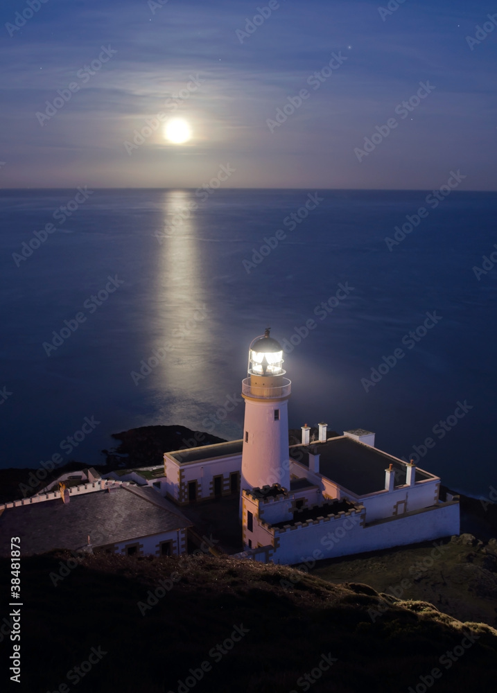 Fototapeta premium Lighthouse with Full Moon Reflecting in Sea