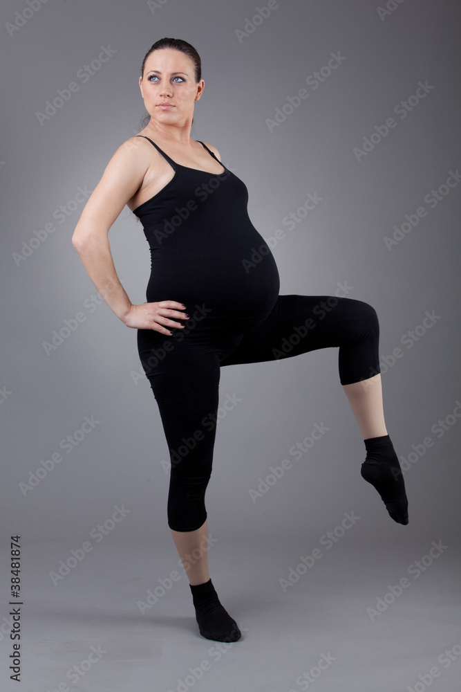 Pregnant woman doing gymnastic exercises on grey background. Pregnant woman doing gymnastic exercises on grey background.