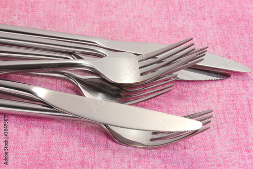 Forks and knives on a pink tablecloth