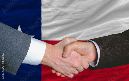 in front of american state flag of texas two businessmen handsha