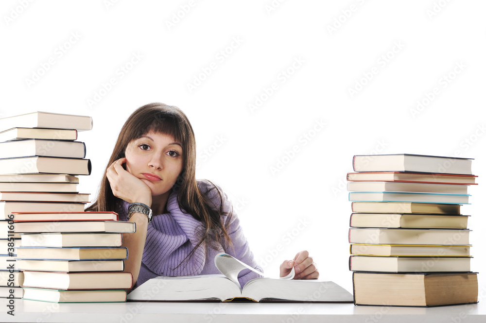 Tired of studies, young Woman is sitting on her desk with books Tired of studies, young Woman is sitting on her desk with books