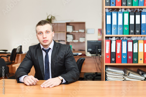 Handsome male business executive sitting behind a bookstand