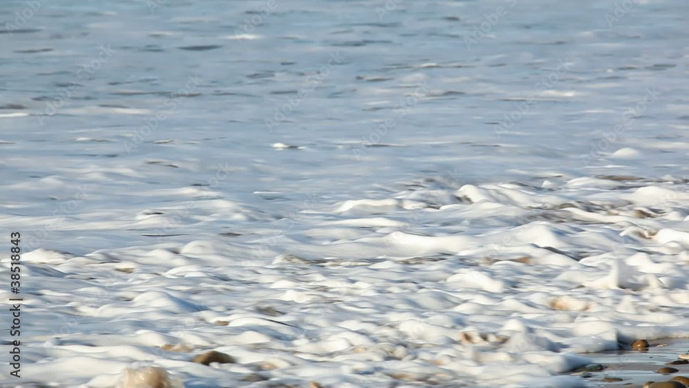 Waves washing over smooth pebbles on a rocky beach Waves washing over smooth pebbles on a rocky beach