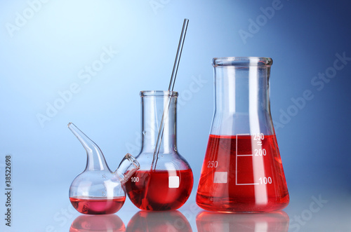 Three flasks with red liquid with reflection on blue background