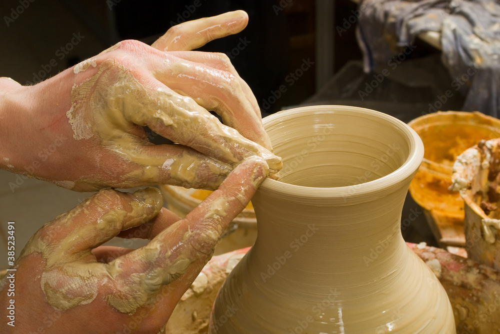 hands of a potter, creating an earthen jar of white clay