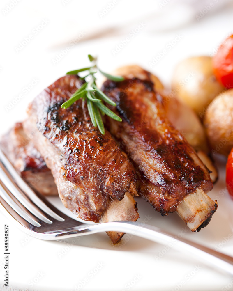 Closeup of pork ribs with rosemary and baked vegetables