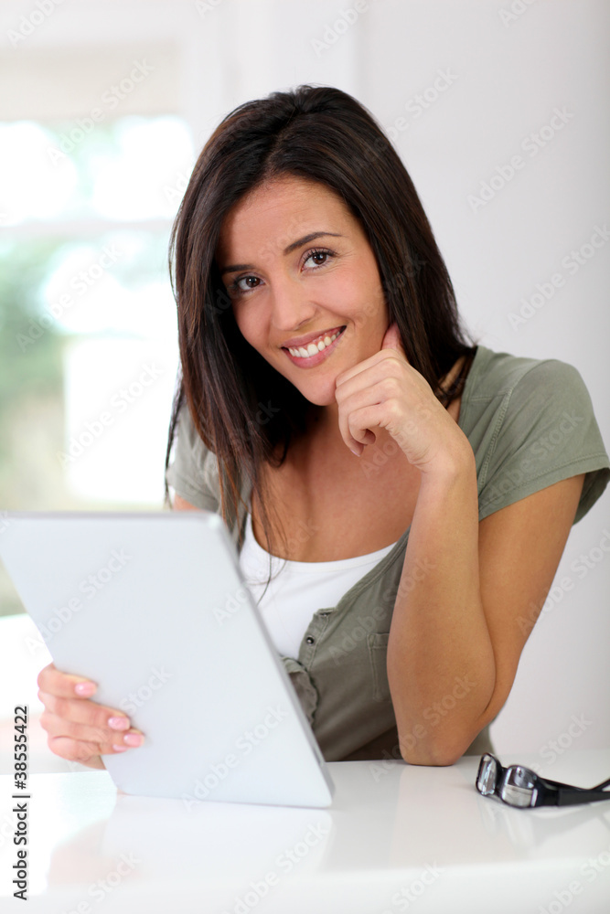 Smiling young woman working on electronic tablet at home Smiling young woman working on electronic tablet at home