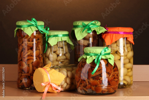 delicious marinated mushrooms in the glass jars on wooden shelf