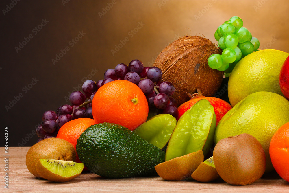Assortment of exotic fruits on wooden table on brown background