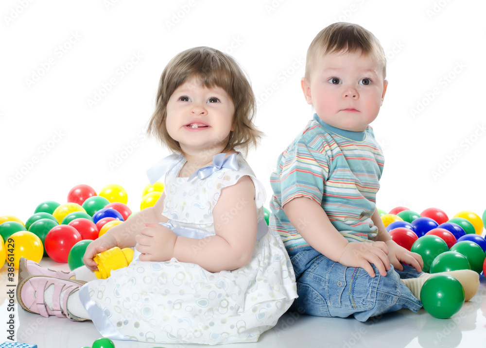 The little girl and boy plays multi-coloured balls isolated The little girl and boy plays multi-coloured balls isolated