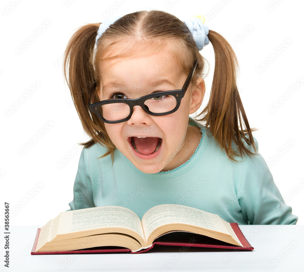 Little girl reads a book while wearing glasses Little girl reads a book while wearing glasses