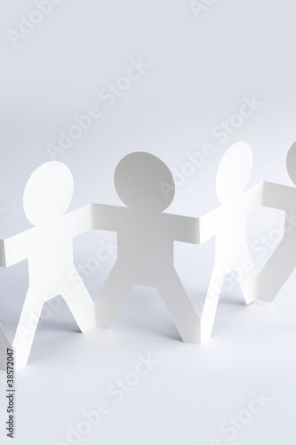 Paper doll team holding hands together united. Teamwork concept
