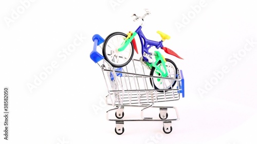 Toy bicycle is in shopping cart, composition rotates photo