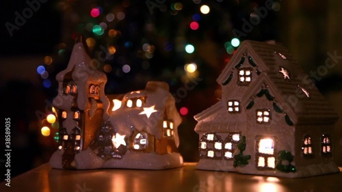 Two toy house-candlestick stand at background of christmas tree photo