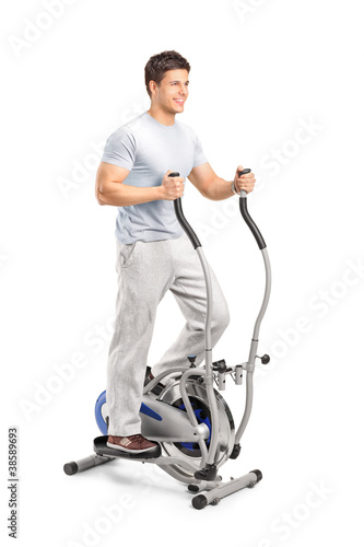 Handsome man exercising on a cross trainer machine photo