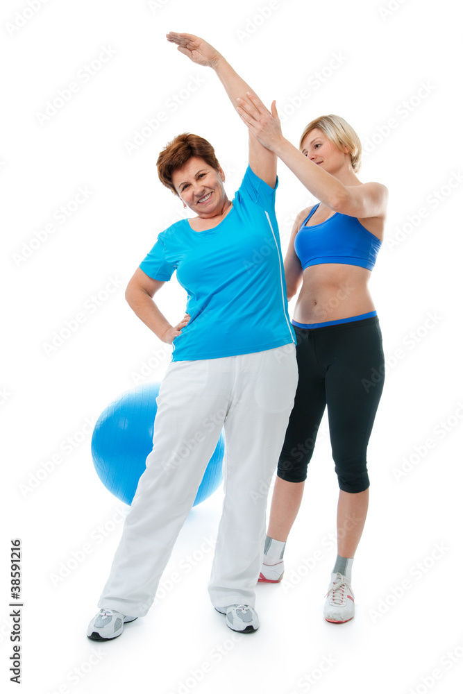 Senior woman doing fitness exercise with help of trainer in gym Senior woman doing fitness exercise with help of trainer in gym