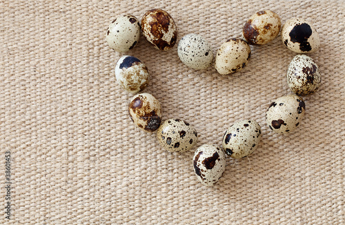 Quail eggs in the shape of heart on a sacking.