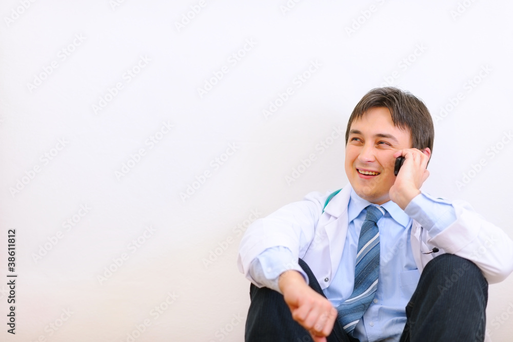Medical doctor sitting on floor and talking mobile Medical doctor sitting on floor and talking mobile