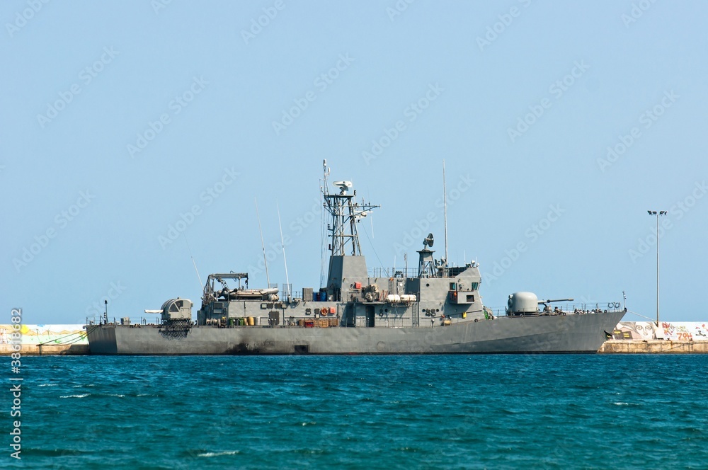 Big battle ship in the dock against blue sky and mountains