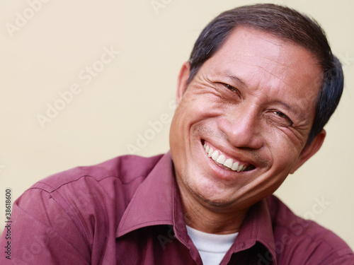 Happy mature Asian man smiling and looking at camera