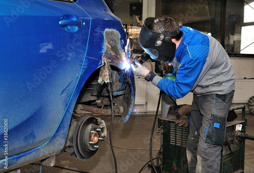 Worker welding a car body.